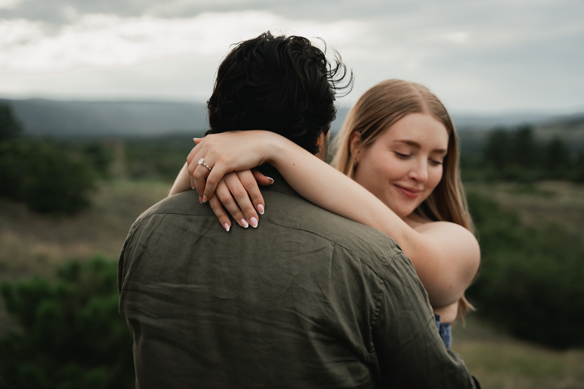 Engaged couple embracing beneath a Colorado sky