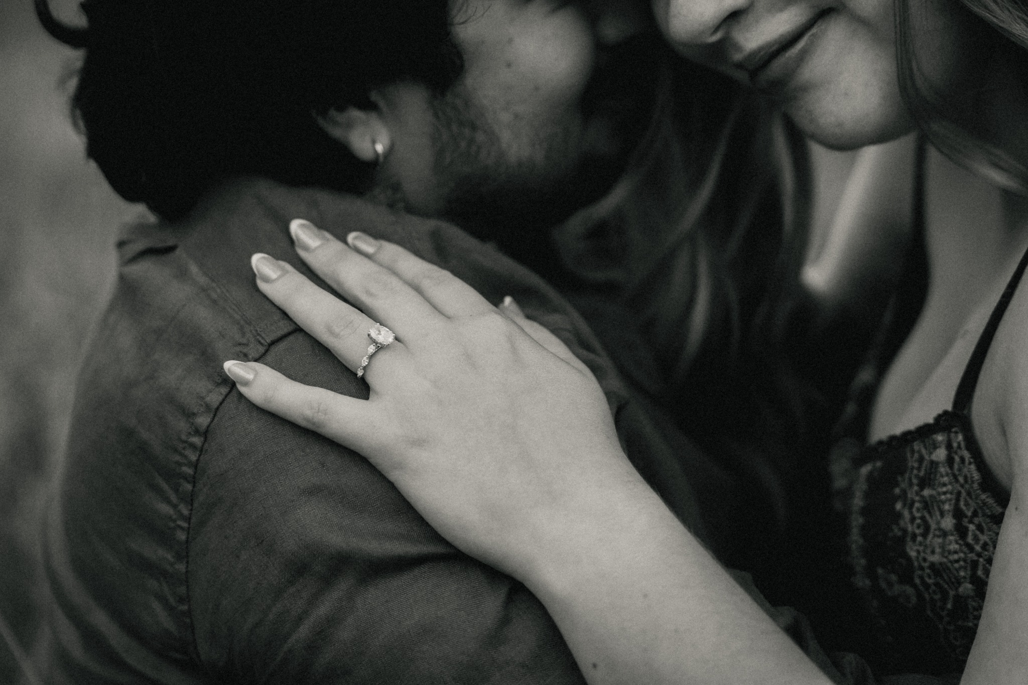 Black and white engagement ring detail during an embrace