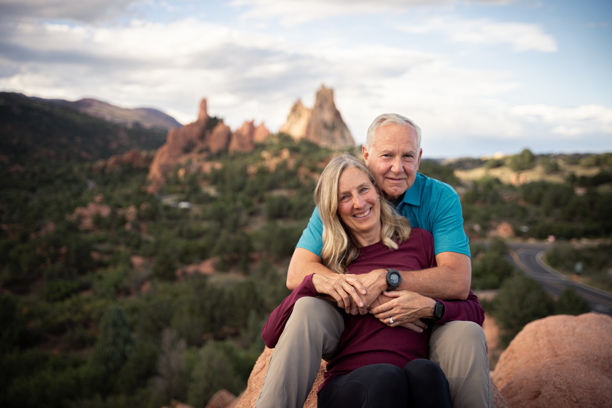 Couple sitting close together among the red rocks at Garden of the Gods