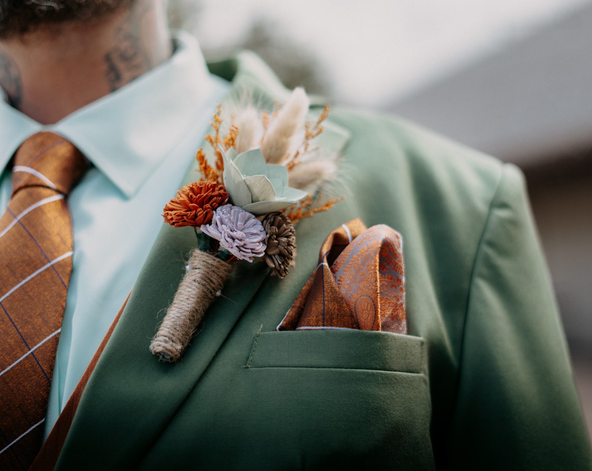 Groom's green suit, boutonniere, tie, and pocket square details