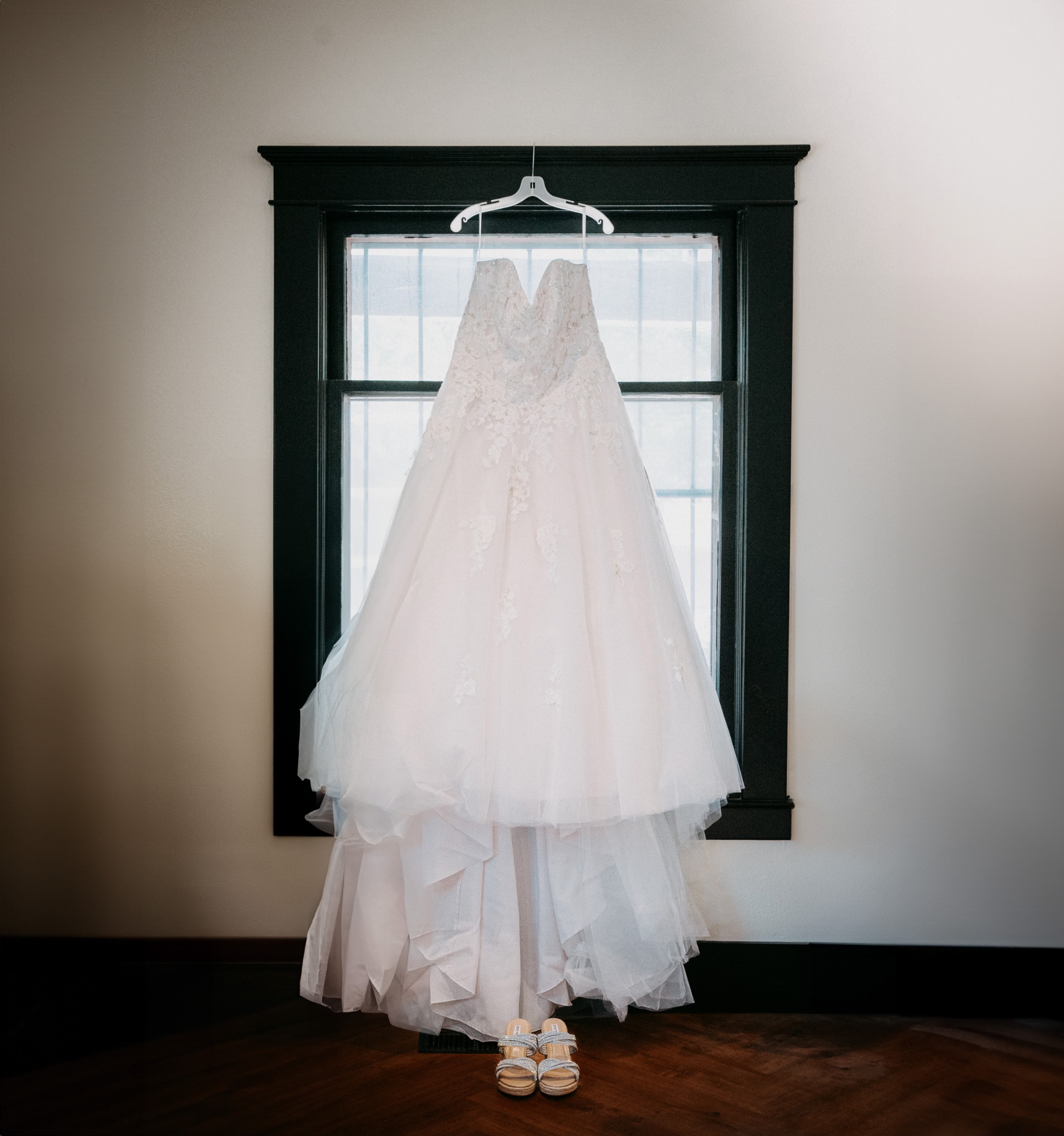 Wedding dress hanging in front of a tall window